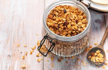 Yulaflı ev yapımı granola ve ahşap masada cam bir kavanozda kurutulmuş meyve.