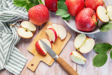 Tahta kesme tahtasındaki taze kırmızı elmalar sağlıklı meyve atıştırmalıkları hazırlıyor.