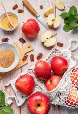 Red apples, nuts, honey, and cinnamon sugar arranged for autumn harvest baking