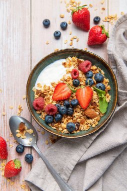 Sağlıklı bir kahvaltı için bir kase granola, yoğurt, çilek, yabanmersini, ahududu ve badem.