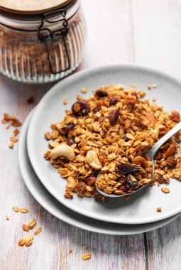 Granola with oats, nuts, and dried fruit serving on a plate out of a jar