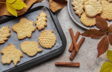 Festive autumn shaped cookies featuring cinnamon sticks and colorful leaves