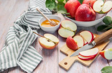Fresh red apples, sliced and whole, complementing a bowl of golden honey