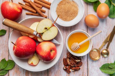 Fresh red apples, honey, cinnamon, and sugar preparing for a fall recipe