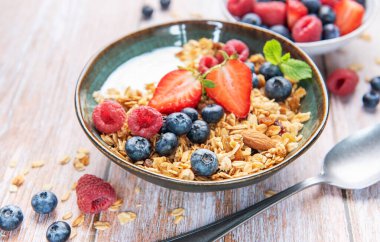 Sağlıklı bir kahvaltı için bir kase granola, yoğurt, çilek, yabanmersini ve ahududu.