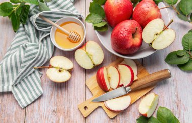 Fresh red apples, sliced and whole, complementing a bowl of golden honey