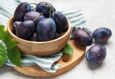 Taze toplanmış erikler hafif arka planda, kırsal ahşap bir kasede dizilmiş.