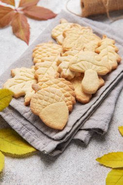 Homemade autumn cookies with fall leaves and twine on a rustic background
