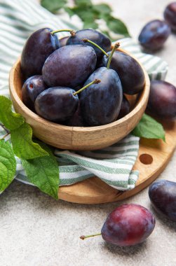 Taze toplanmış erikler hafif arka planda, kırsal ahşap bir kasede dizilmiş.