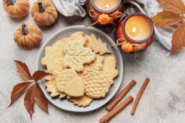 Fall themed shortbread cookies arranged on a plate with cinnamon sticks and seasonal decorations