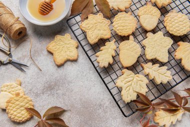 Sonbahar temalı kurabiyeler tel askıda soğuyor bal, sicim ve dökülen yapraklarla.