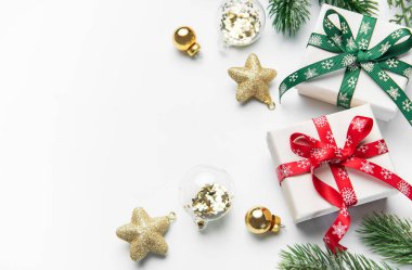 Hediye kutuları, süsler, kırmızı böğürtlenler ve beyaz arka planda köknar dalları olan tatil öğeleri