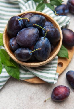 Taze toplanmış erikler hafif arka planda, kırsal ahşap bir kasede dizilmiş.