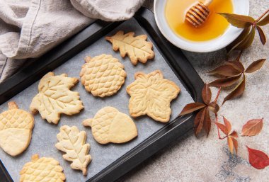 Taze pişmiş sonbahar temalı kurabiyeler bal ve sonbahar yapraklı bir tepside düzenlenir.