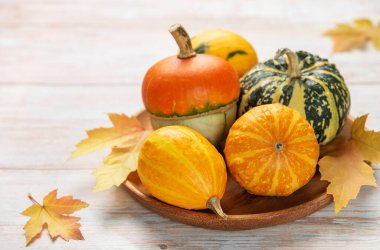 Çeşitli küçük su kabakları ve yaprakları olan balkabakları ahşap bir yüzeyde hasat mevsimini resmediyordu.