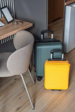 Renkli bavullar modern bir otel odasında bekliyor. Tatil ve seyahati simgeliyor.