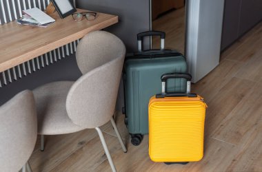 Renkli bavullar modern bir otel odasında bekliyor. Tatil ve seyahati simgeliyor.