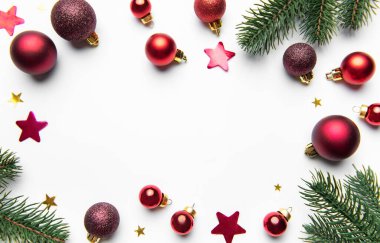 Kırmızı takılar, parıldayan yıldızlar ve çam dalları beyaz bir zemin oluşturuyor.