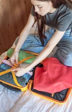 Giysileri turuncu bir bavula saran, seyahat için hazırlanan bir kadın.