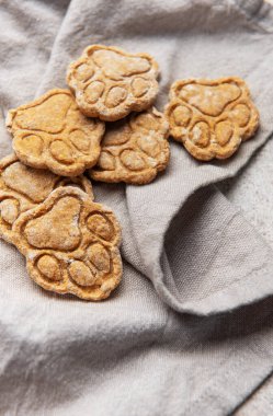 Gri keten peçetenin üzerinde duran pençe izi şeklinde ev yapımı köpek bisküvileri.