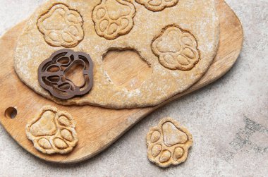 Hamur, keski ve pençe izli kurabiyeler ahşap bir tahtanın üzerinde, ev yapımı evcil hayvan maması hazırlıyorlar.