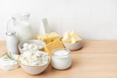 Tahta bir masaya kurulmuş çeşitli süt ürünleri, besleyici kahvaltı seçenekleri sunuyor.