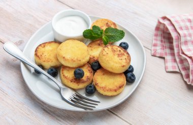 Tatlı şurup, taze yaban mersini ve ahşap bir masada ekşi krema, mükemmel bir kahvaltı.