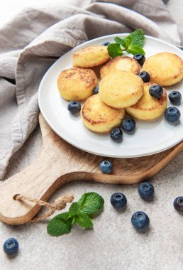 Syrniki, tatlı süzme peynir krepleri, kahvaltıda taze yaban mersini ve nane ile servis ediliyor.