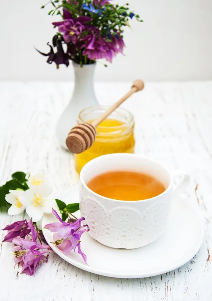 Tasse Tee, Honig und Blumen auf einem alten hölzernen HintergrundKopje thee, honing en bloemen — Stockfoto