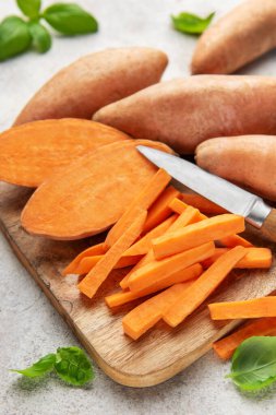 Mutfak tahtasının üzerinde fesleğen yapraklarıyla doğranmış taze patates.