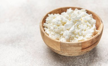 Süzme peynir ahşap kaseyi dolduruyor, sağlıklı süt ve yüksek proteini temsil ediyor.