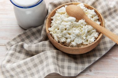 Köhne ahşap bir kasede taze süzme peynir ve kareli bir masa örtüsü.