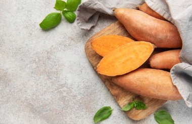 Taze patatesler ve fesleğenli, sağlıklı organik sebzelerle ahşap bir tahtanın üzerinde yarımlar.