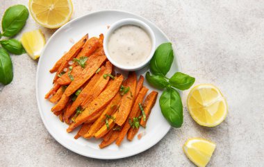 Kremalı sos, taze fesleğen ve limonla servis edilen patates kızartması.