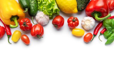 Taze renkli sebzeler ve baharatlar beyaz arka planda canlı bir sınır oluşturuyor.