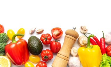 Taze renkli sebzeler ve baharatlar beyaz arka planda bir sınır oluşturuyor.