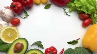 Beyaz arka planda hareket eden taze organik sebzeler ve meyvelerden oluşan dairesel çerçeve