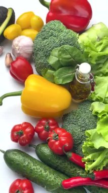 Renkli taze sebze seçimi ve beyaz arka planda izole edilmiş bir şişe zeytinyağı.