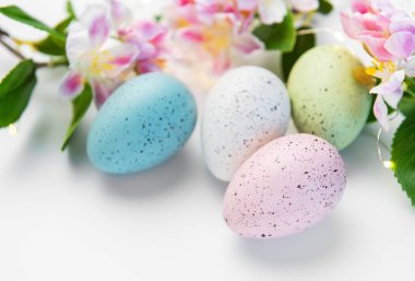 Pastel benekli yumurtalar, narin bahar çiçekleri ve parlayan ışıklar.