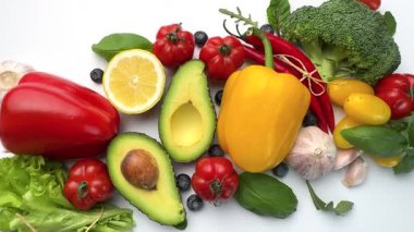 Temiz beyaz arka planda hareket eden taze organik sebzeler ve meyveler.