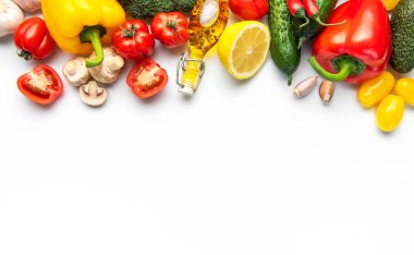 Taze sebzeler ve beyaz yüzeye yerleştirilmiş bir şişe zeytinyağı.