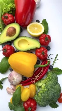 Temiz beyaz arka planda hareket eden taze organik sebzeler ve meyveler.