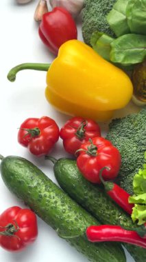 Temiz beyaz arka planda dönen çiğ, organik sebzeler ve zeytinyağı renkli seçim