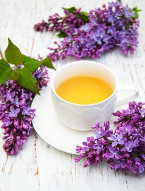 Fincan çay ve eflatun çiçekler