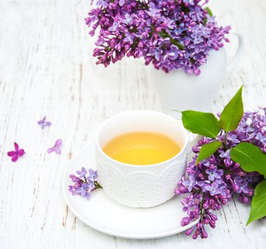 Fincan çay ve eflatun çiçekler