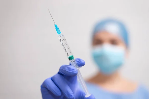 A medical syringe with needle filled with medicine or vaccine in the hand of a doctor or nurse. Vaccination against covid-19, flu, coronavirus, ebola, TB or injection of pain relief, insulin.
