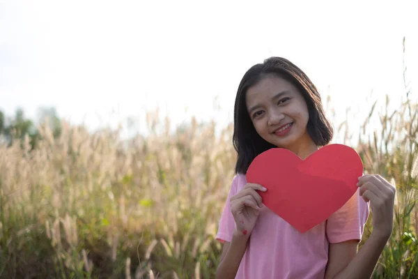 Genç Asyalı Kız Arka Planda Kırmızı Kalp Kağıdı Tutuyor — Stok fotoğraf