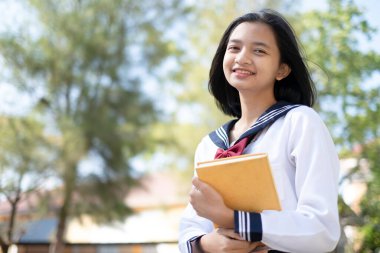 Güzel Asyalı öğrenci okulda kitap tutuyor..