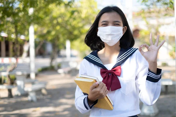 Ασιάτης Φοιτητής Κρατήσει Βιβλίο Και Φορούν Μάσκα Στο Σχολείο Στολή — Φωτογραφία Αρχείου