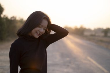 Gün batımında, uzun yolda genç Asyalı bir kızın portresi..